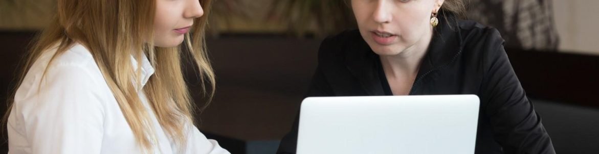 Two professionals collaborating on a laptop, representing multilingual communication in legal support.