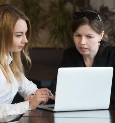 Two professionals collaborating on a laptop, representing multilingual communication in legal support.