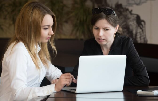 Two professionals collaborating on a laptop, representing multilingual communication in legal support.