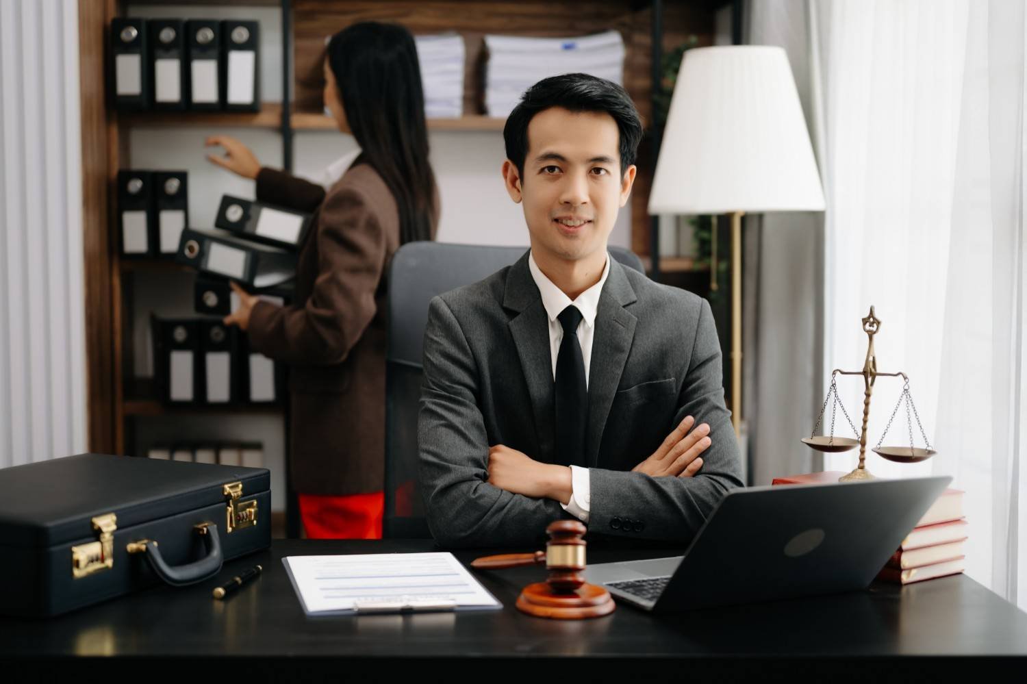 Confident immigration attorney in office with legal assistant organizing case files, symbolizing law firm efficiency and growth.