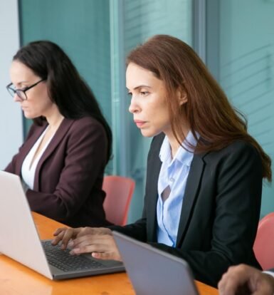 Immigration professionals ensuring H-1B employer compliance by reviewing documents and regulations on their laptops.