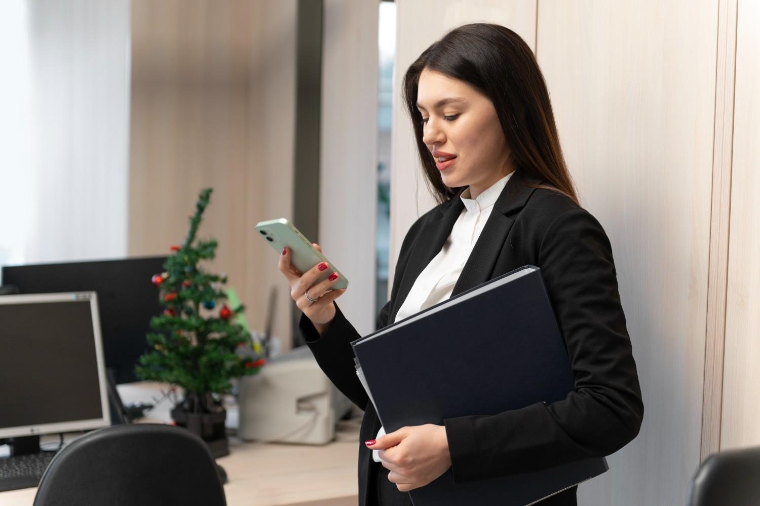 A professional woman in a business suit tracking an H-1B petition delivery on her phone while holding legal documents.