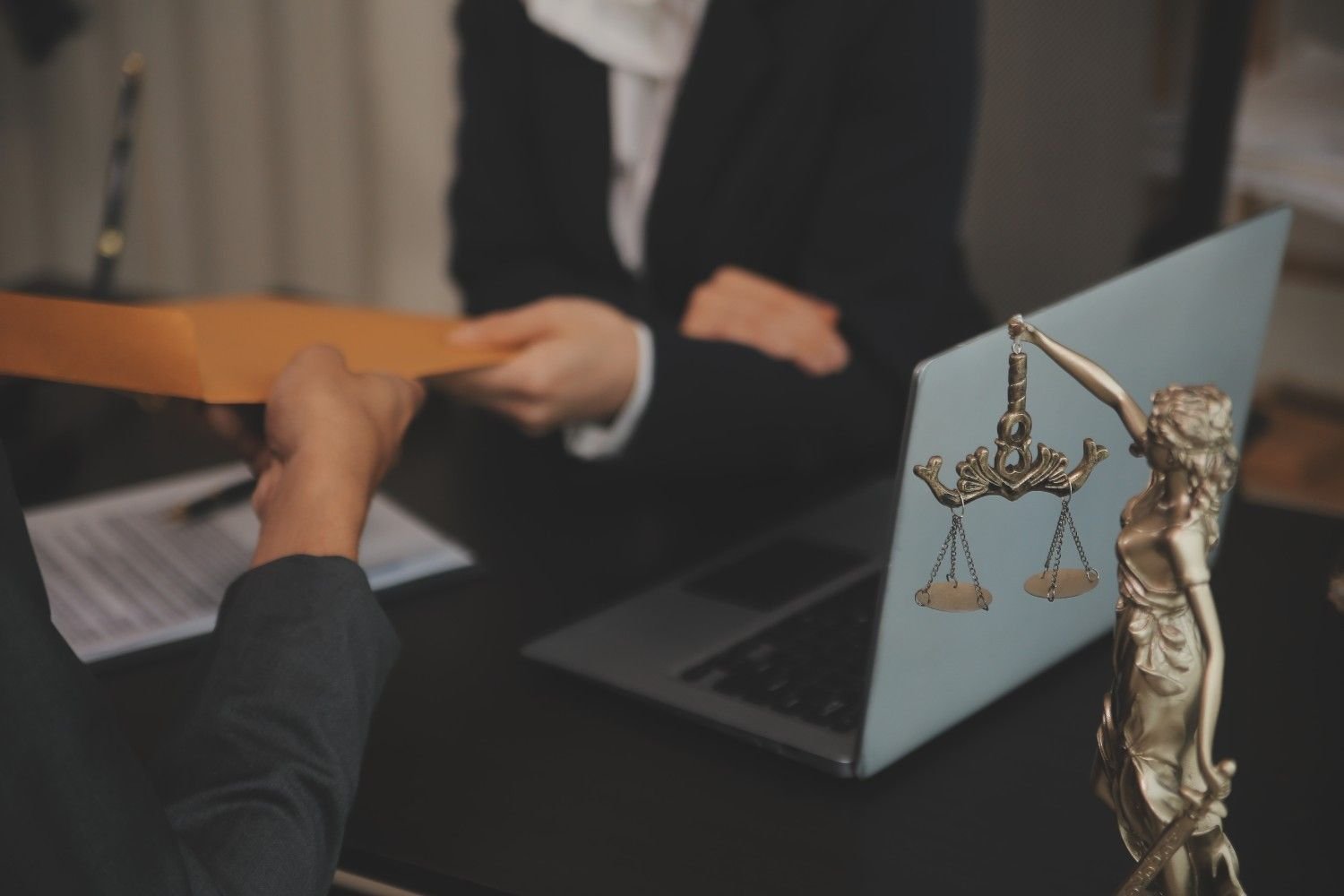 Immigration attorney receiving documents from a client with legal scales in the foreground