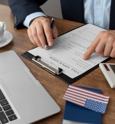 Immigration attorney reviewing a visa application form with a laptop, U.S. passport, and American flag—outsourcing immigration paralegal services for Form I-907 processing.