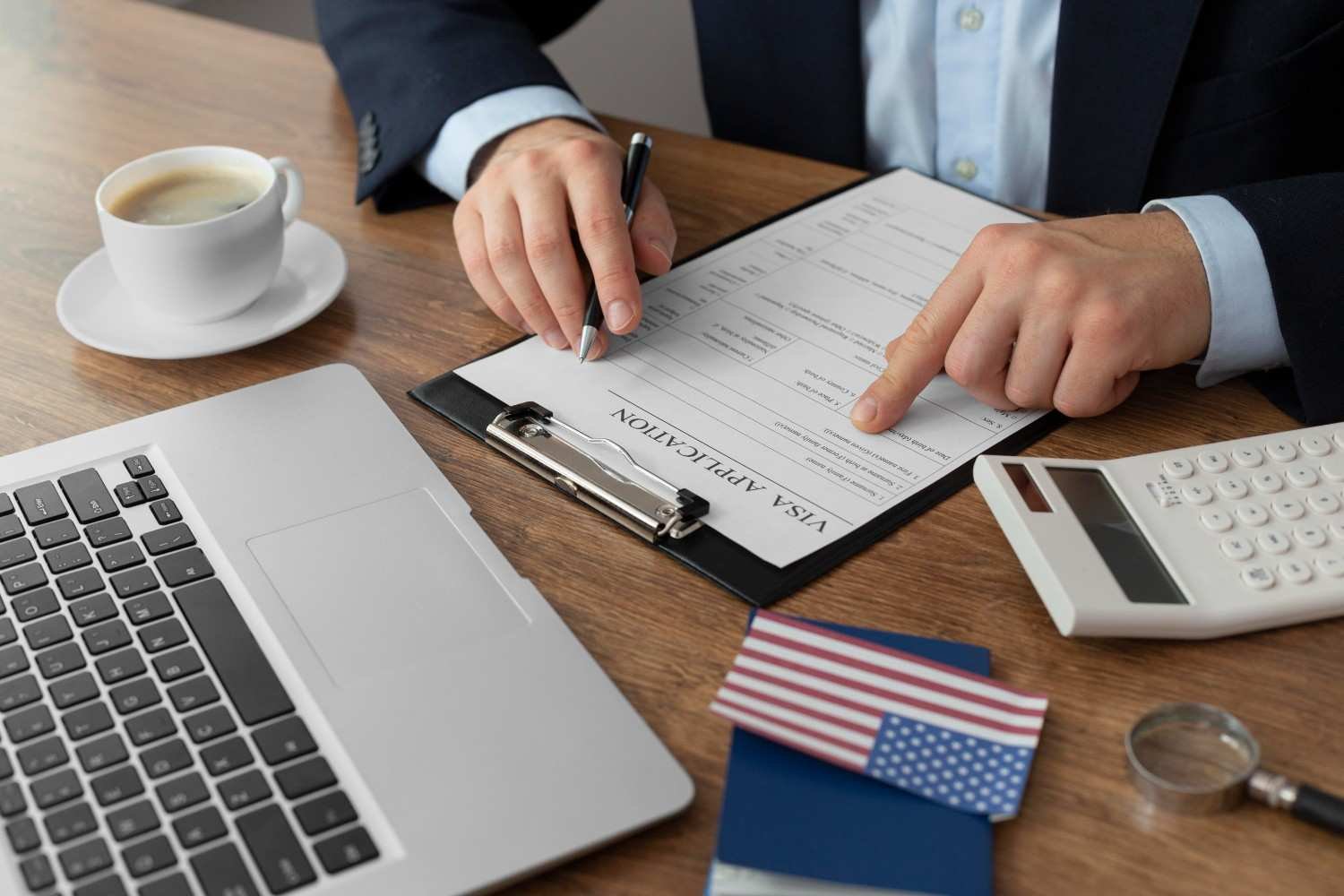 Immigration attorney reviewing a visa application form with a laptop, U.S. passport, and American flag—outsourcing immigration paralegal services for Form I-907 processing.