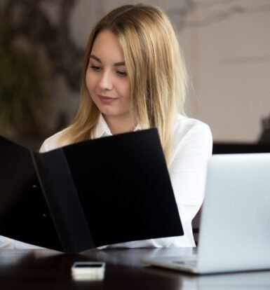 A professional woman reviewing USCIS case approval documents with a laptop and folder.