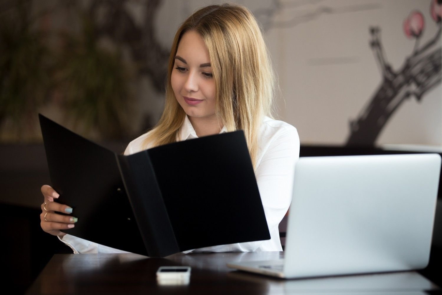 A professional woman reviewing USCIS case approval documents with a laptop and folder.