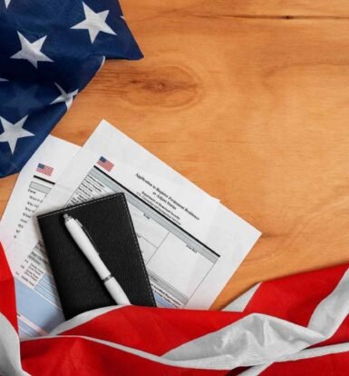 USCIS case status tracking documents, U.S. flag, and a pen on a wooden surface.