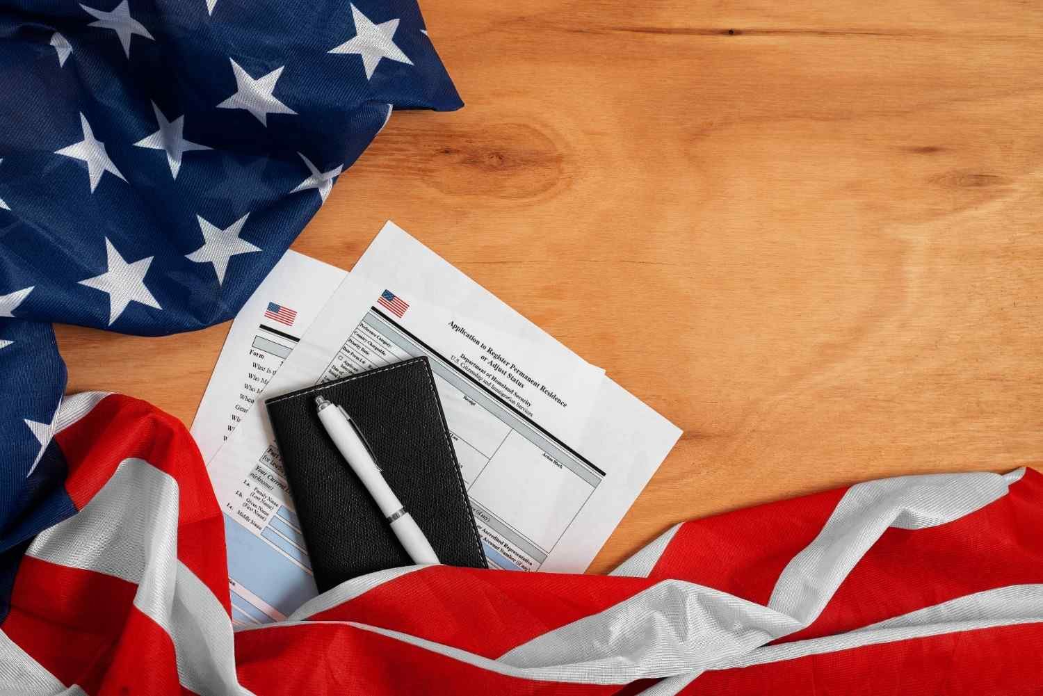 USCIS case status tracking documents, U.S. flag, and a pen on a wooden surface.