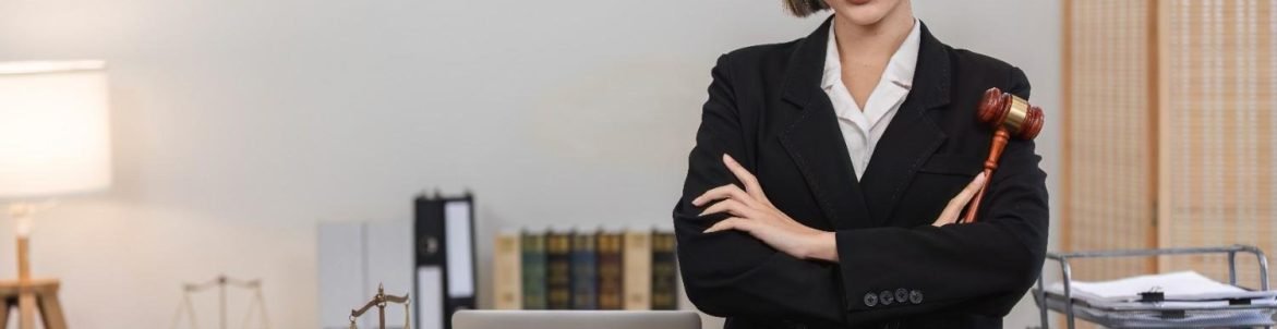Confident female attorney in a law office, holding a gavel, with legal books, scales, and a laptop on the desk — illustrating the efficiency and professionalism gained from Virtual Legal Assistant Benefits for Small Law Firms.