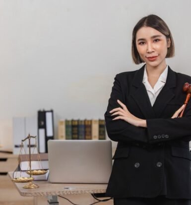 Confident female attorney in a law office, holding a gavel, with legal books, scales, and a laptop on the desk—illustrating the efficiency and professionalism gained from Virtual Legal Assistant Benefits for Small Law Firms.