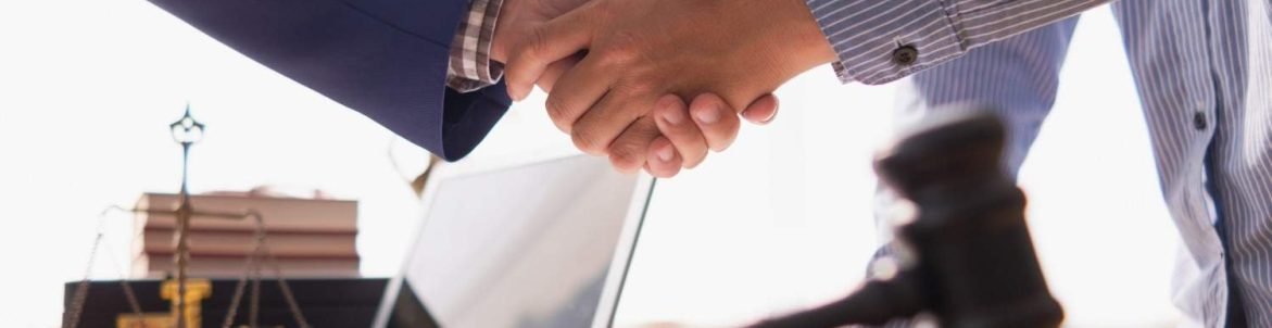 Lawyer and client shaking hands in an office, symbolizing trust and effective legal communication.