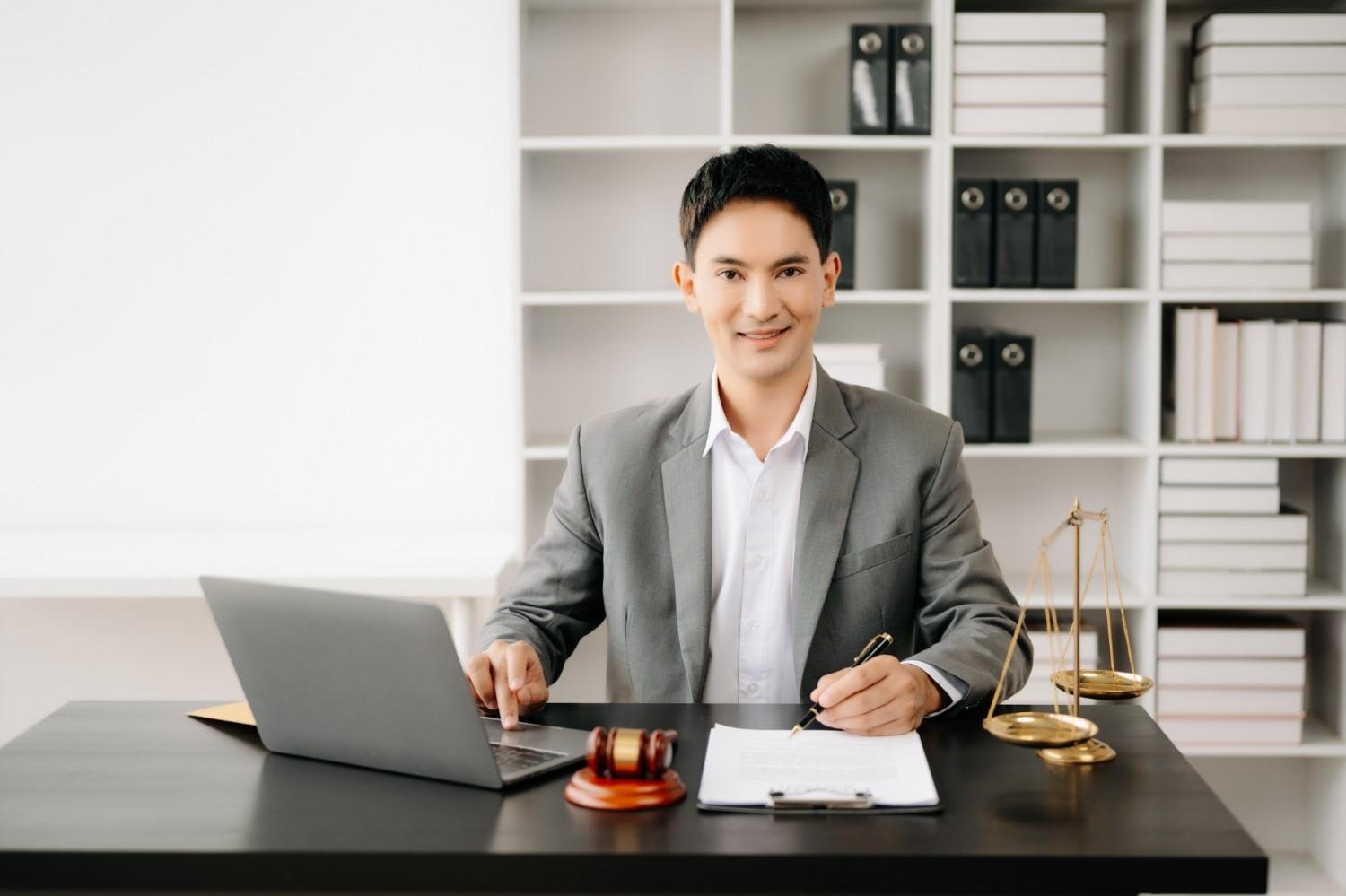 Confident lawyer working efficiently with a laptop and legal documents, representing the benefits of Virtual Legal Assistants for Law Firms.
